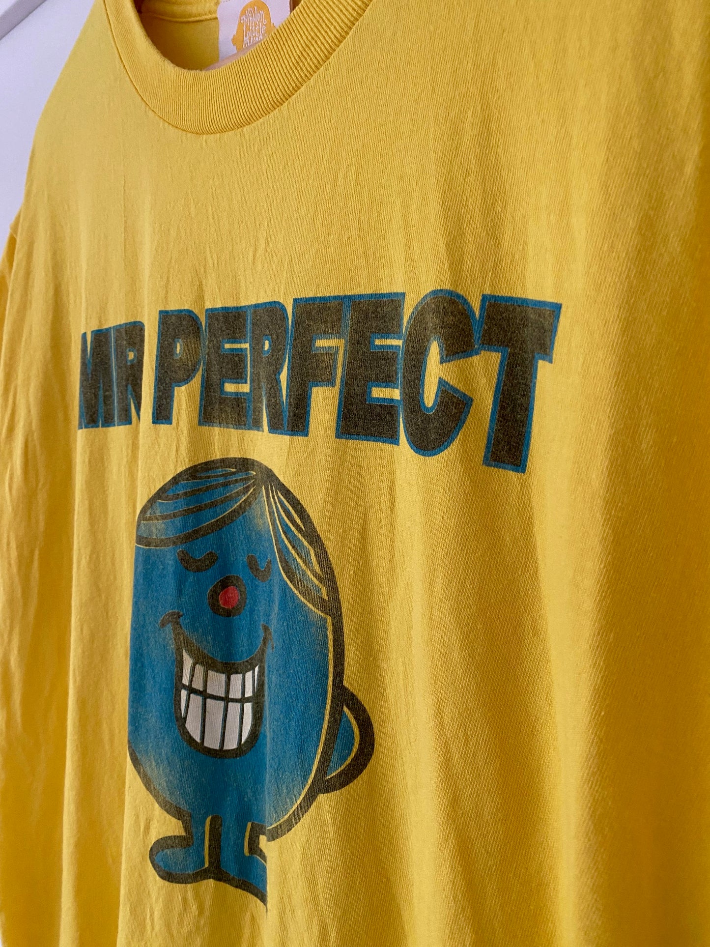 close-up of mr. perfect bright yellow t-shirt with a smile on a blue caracter