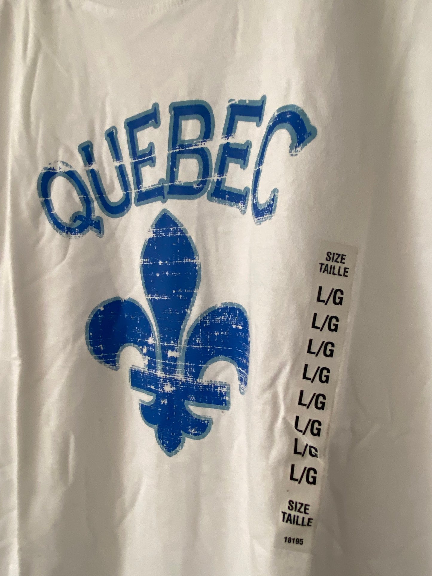 close-up white t-shirt with the word quebec and under a bleu fleur de lys